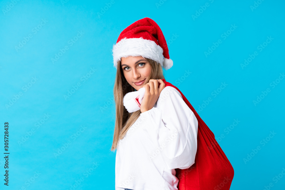 Young blonde woman picking up a bag full of presents over isolated background Young blonde woman picking up a bag full of presents over isolated background
