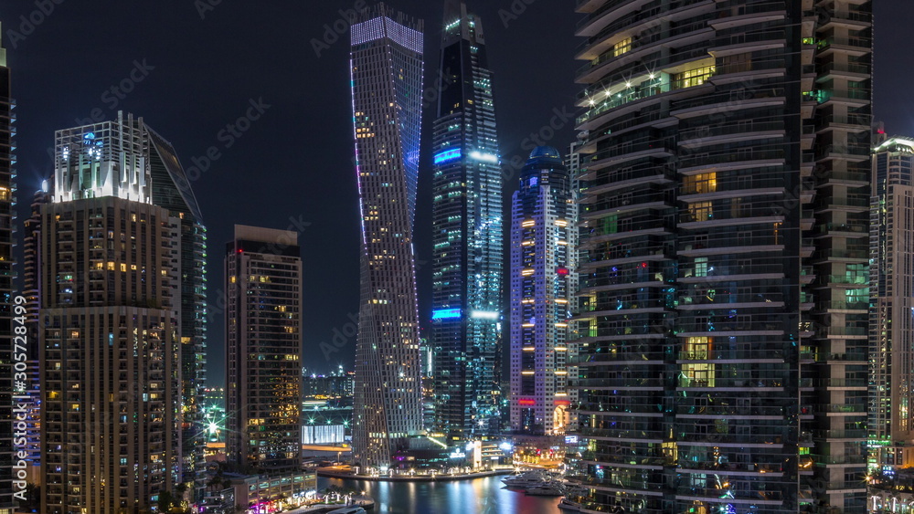 Aerial view of Dubai Marina residential and office skyscrapers with waterfront night timelapse