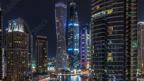 Aerial view of Dubai Marina residential and office skyscrapers with waterfront night timelapse