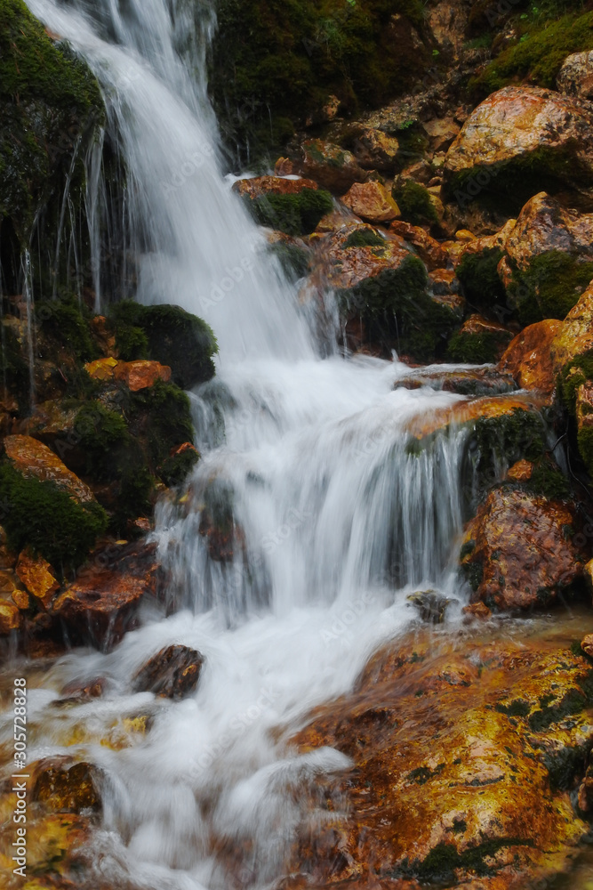 Fototapeta premium Ruscello alpino con cascata d'acqua tra le rocce
