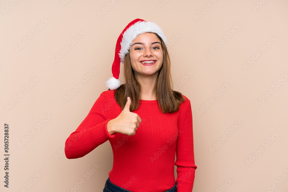 Young girl with christmas hat over isolated background giving a thumbs up gesture Young girl with christmas hat over isolated background giving a thumbs up gesture
