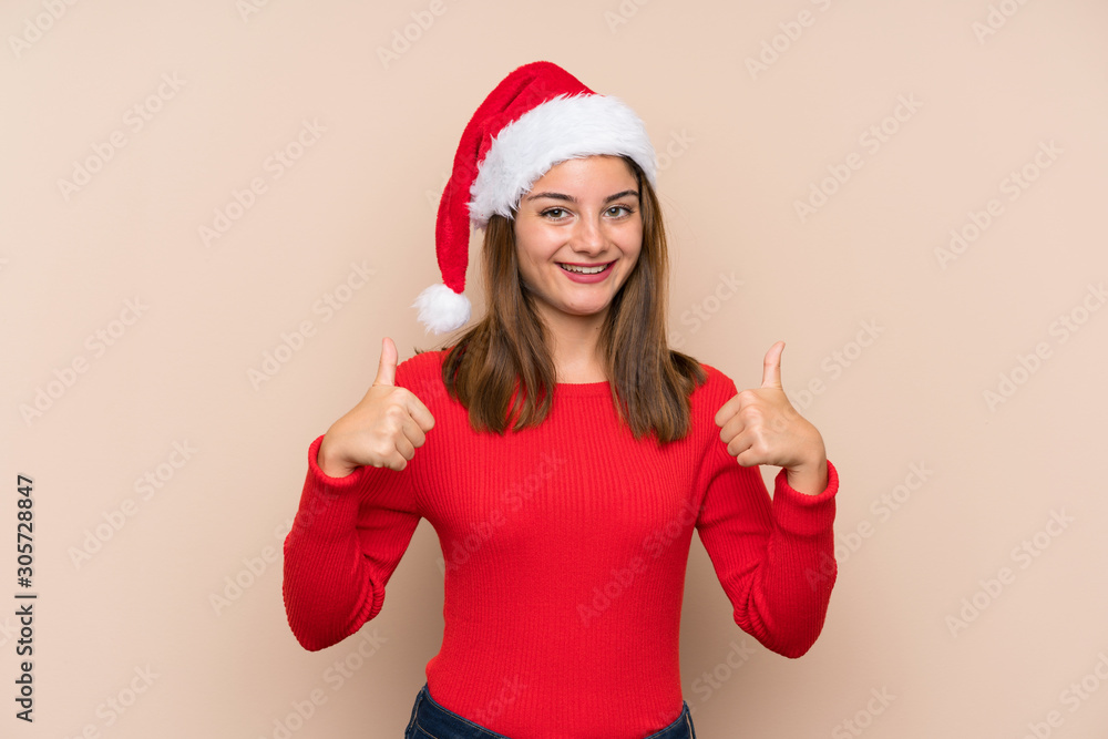 Young girl with christmas hat over isolated background giving a thumbs up gesture Young girl with christmas hat over isolated background giving a thumbs up gesture