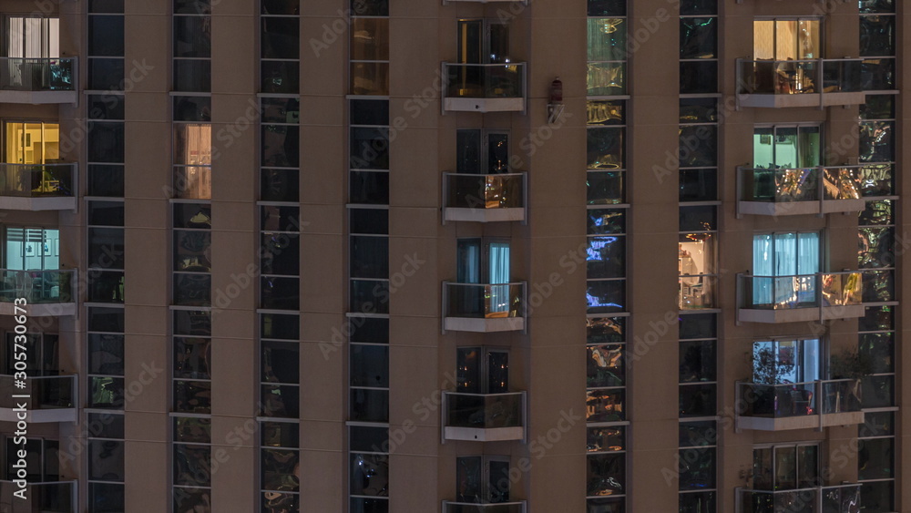 Rows of glowing windows with people in apartment building at night. Rows of glowing windows with people in apartment building at night.