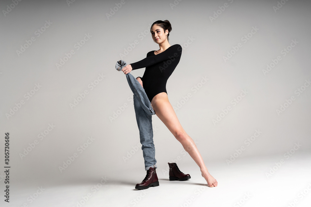 Obraz premium womens bodysuit, black boots, blue jeans. Tall sexy short haired model posing in a fashionable bow on a white background