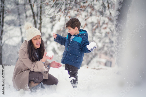 Young  beautiful mom and her cute little boy playing in the snow  enjoying winter