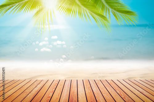 Blur tropical beach with bokeh sun light wave and palm tree on empty old wood table abstract background.