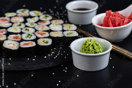 Sushi with fish, with cucumber, with eel, with avocado. Wrapped in Nori Seaweed. Food for vegetarians. Soy sauce, ginger, wasabi in white bowls. Copy space.