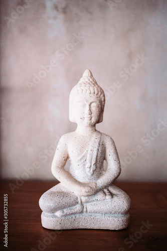 White Buddha statue as home decor  decoration on wooden surface.