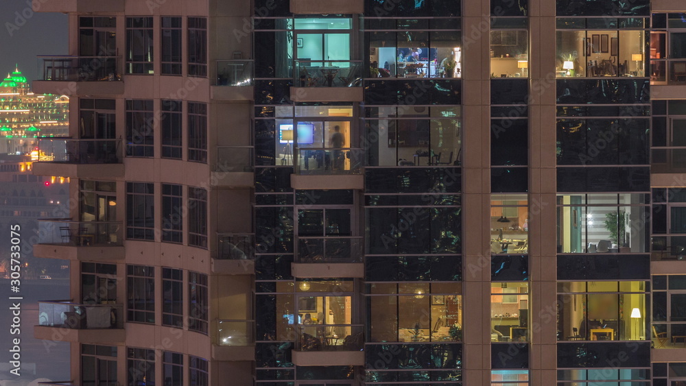 Rows of glowing windows with people in apartment building at night. Rows of glowing windows with people in apartment building at night.