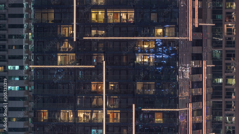 Rows of glowing windows with people in apartment building at night. Rows of glowing windows with people in apartment building at night.
