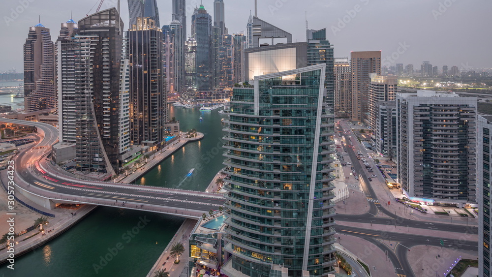 Obraz premium Aerial view of Dubai Marina residential and office skyscrapers with waterfront day to night timelapse
