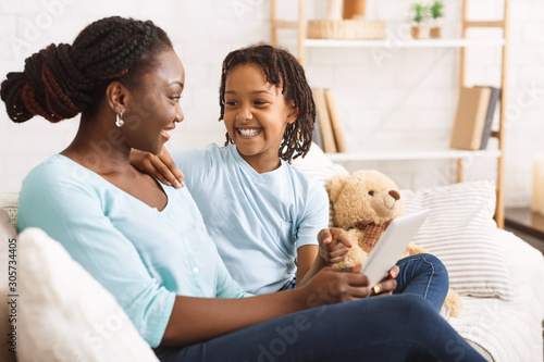 Black mother showing her daughter some photos