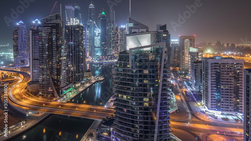 Aerial view of Dubai Marina residential and office skyscrapers with waterfront night timelapse