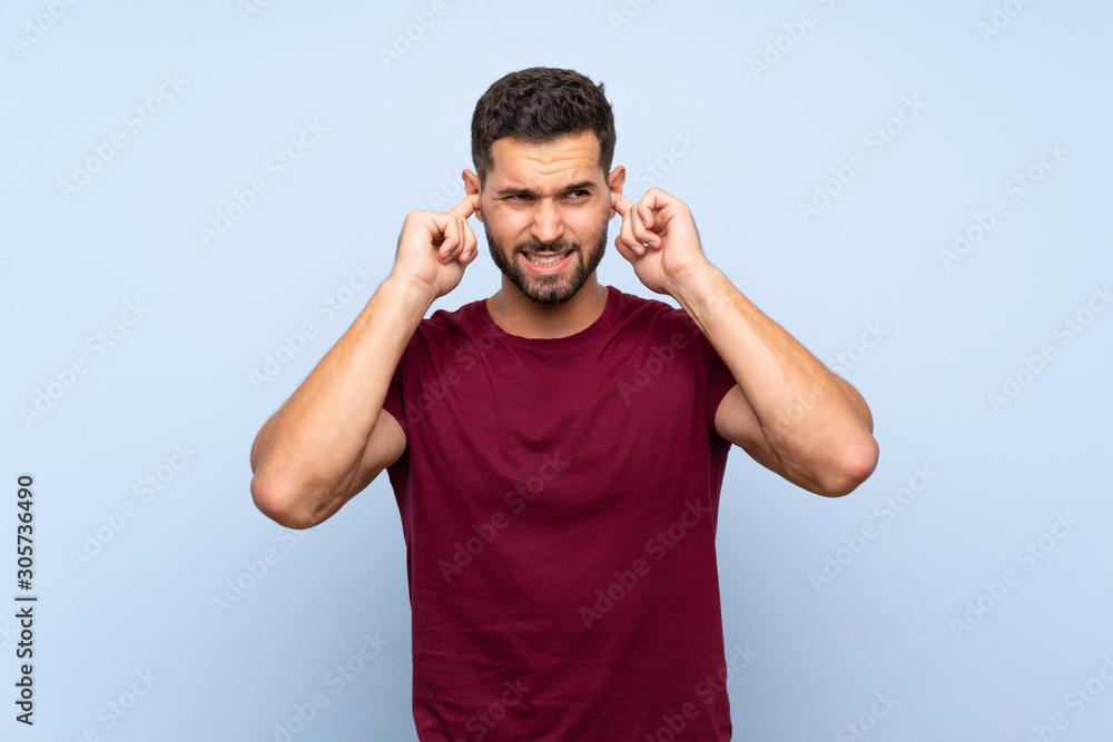 Fototapeta premium Handsome man over isolated blue background frustrated and covering ears