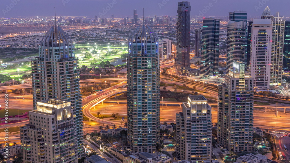 Obraz premium Dubai Marina skyscrapers and jumeirah lake towers view from the top aerial day to night timelapse in the United Arab Emirates.