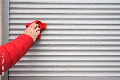  hand with a rag cleans sunblind on window photo