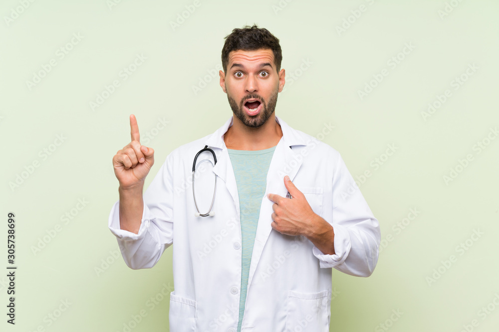 Young doctor man over isolated green wall with surprise facial expression Young doctor man over isolated green wall with surprise facial expression