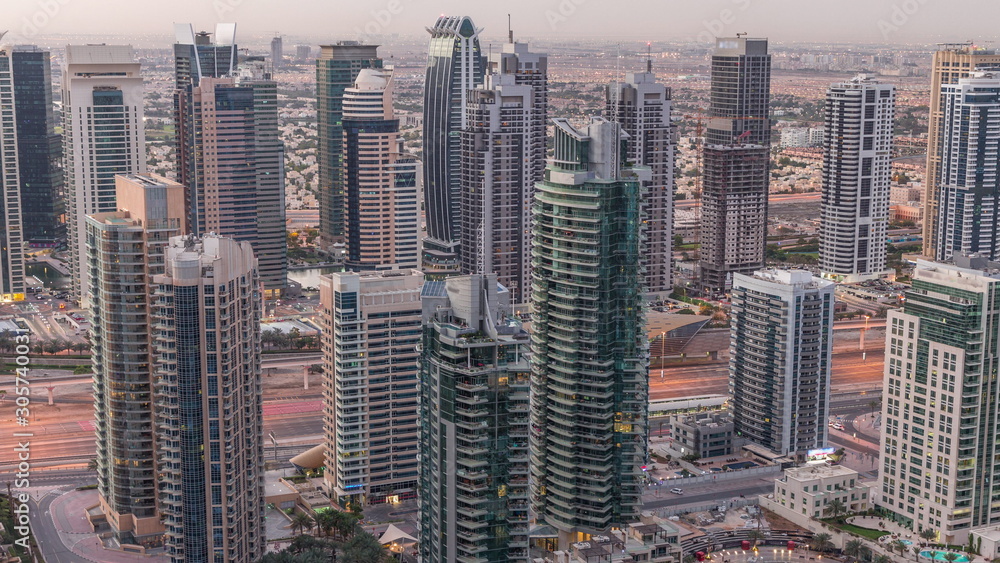 Fototapeta Dubai Marina skyscrapers and jumeirah lake towers view from the top aerial night to day timelapse in the United Arab Emirates.