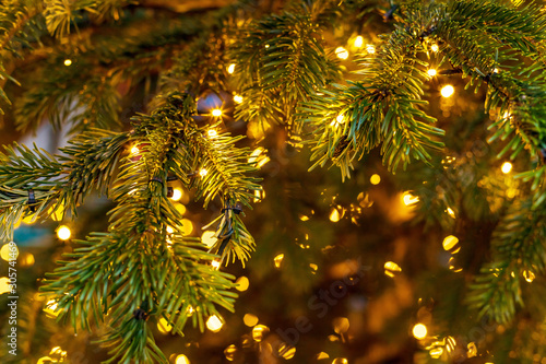 Outdoor decorated Christmas tree with light garland, selective focus