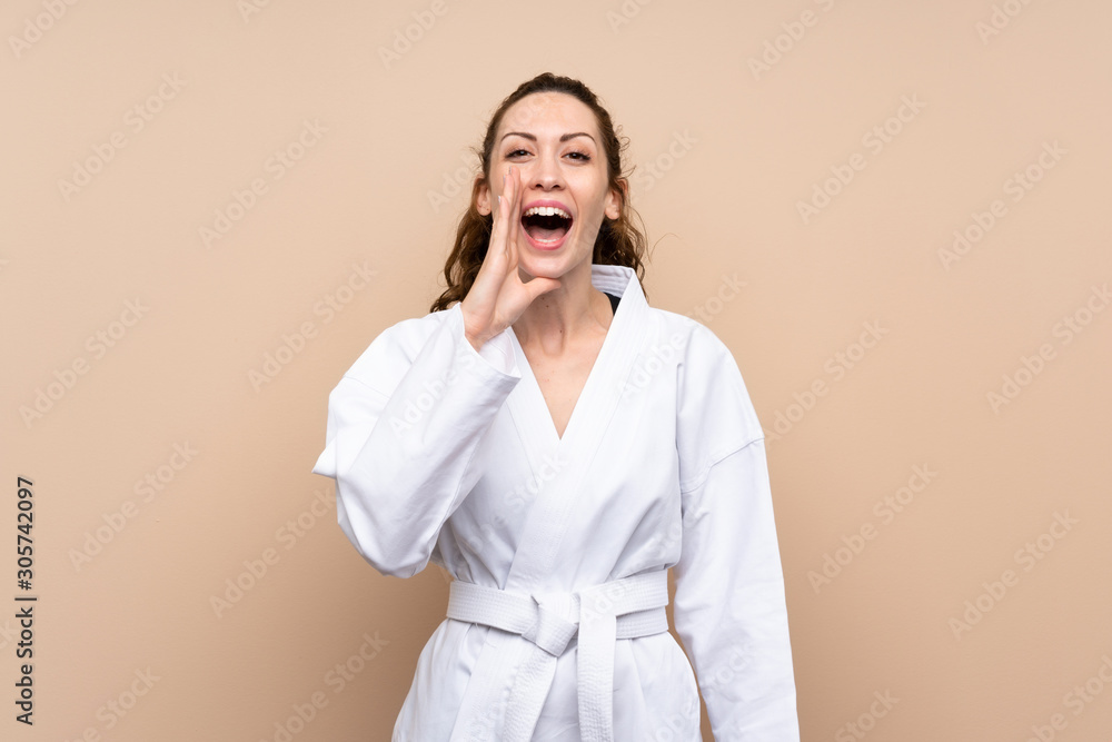 Young woman doing karate shouting with mouth wide open Young woman doing karate shouting with mouth wide open