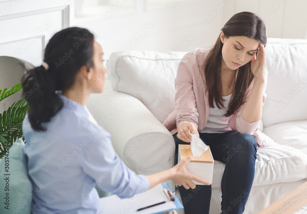 Thoughtful unhappy young lady taking napkins from tissue box Thoughtful unhappy young lady taking napkins from tissue box