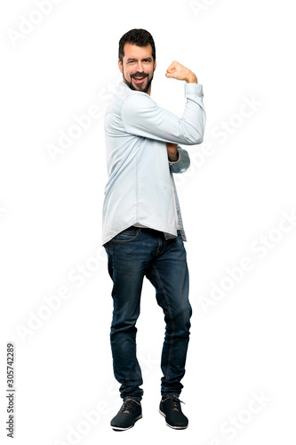 Full-length shot of Handsome man with beard doing strong gesture over isolated white background