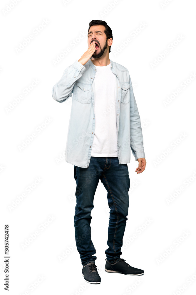 Full-length shot of Handsome man with beard yawning and covering wide open mouth with hand over isolated white background Full-length shot of Handsome man with beard yawning and covering wide open mouth with hand over isolated white background