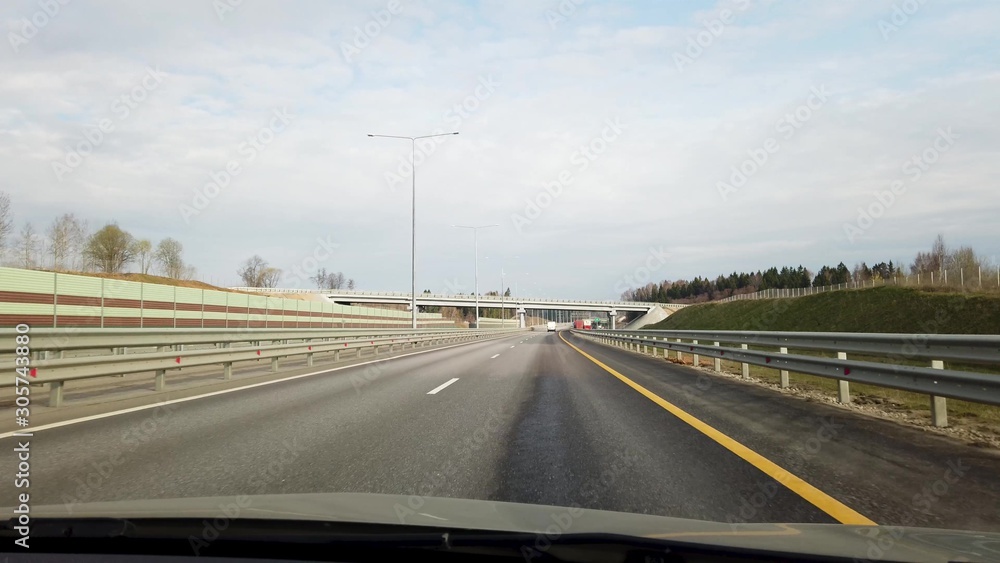 Fototapeta premium The car moves on an asphalt highway. Front view through the windshield.
