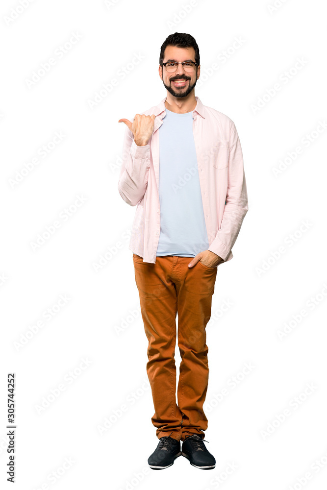 Full-length shot of Handsome man with beard pointing to the side to present a product over isolated white background