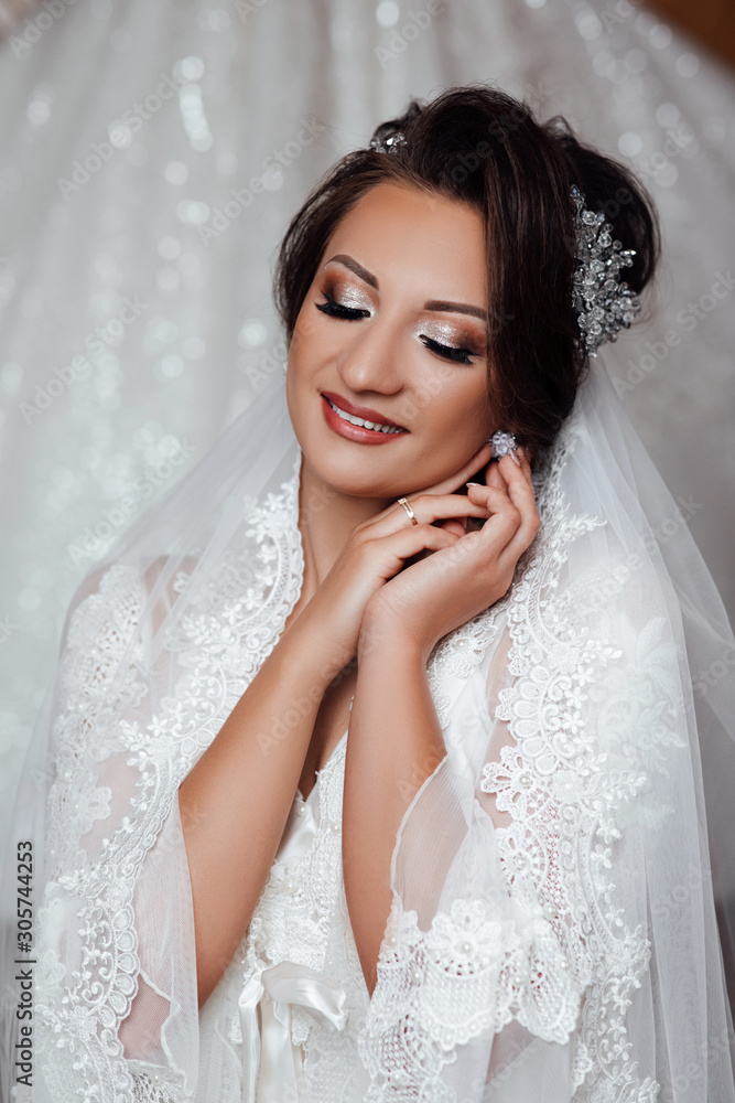 Bride's preparation at home before the wedding ceremony. Beautiful bride dresses earrings. Beautiful bride with stylish make up and hair style. Sexy bride. Preparing the bride for the upcoming wedding Bride's preparation at home before the wedding ceremony. Beautiful bride dresses earrings. Beautiful bride with stylish make up and hair style. Sexy bride. Preparing the bride for the upcoming wedding