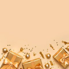 Merry Christmas and Happy Holidays greeting card. Beautiful golden gift balls ribbons confetti stars on gold background top view Flat lay. New Year presents Festive decorations 2020 celebration