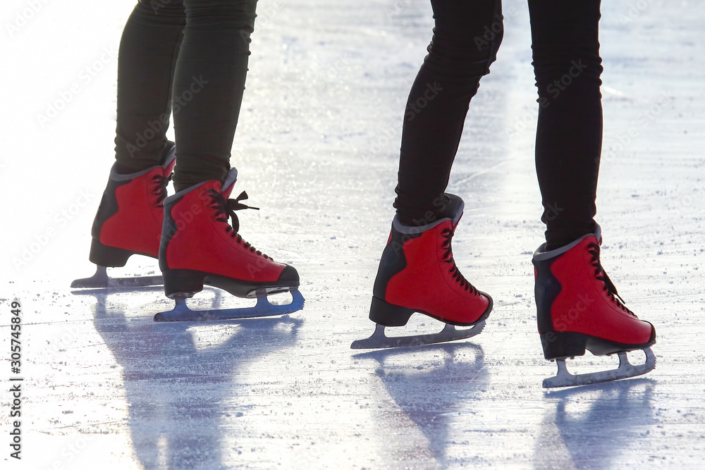 feet in red skates on an ice rink. Sport and entertainment. Rest and winter holidays.