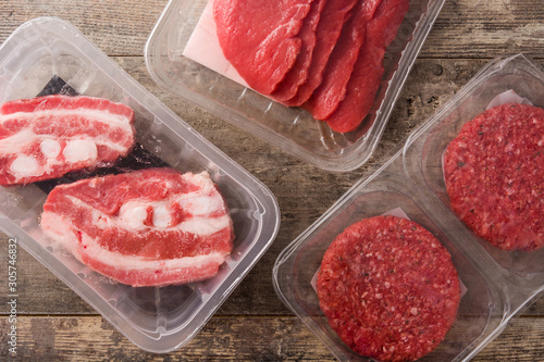 Different types of meat packaged in plastic on wooden table. Top view	