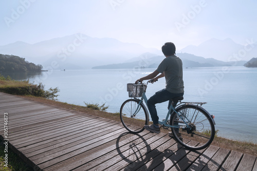 young men riding a bicycle on bike trail at the lake in the morning. Active people. Outdoors