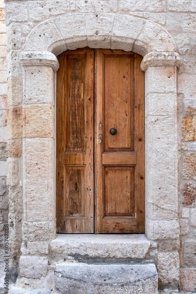 The stone portal of the building and the wooden paneled door.