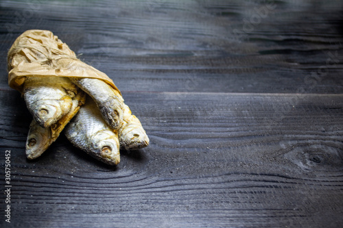 dried stockfish in a paper bag on a wooden board. Selective focus. Blur background
