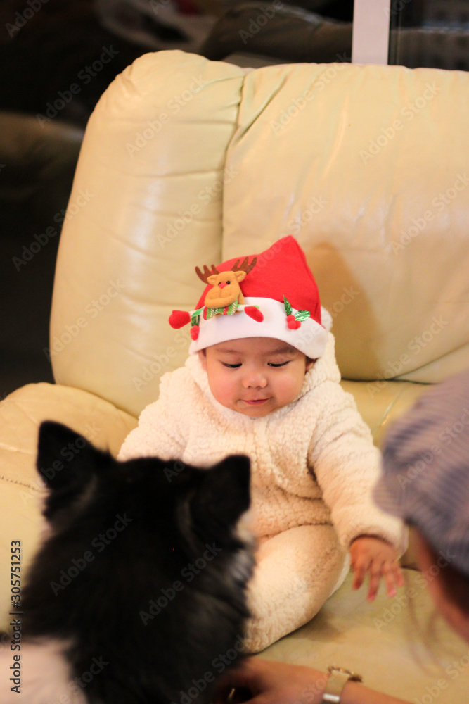 Obraz premium Baby with Santa hat sitting on the sofa