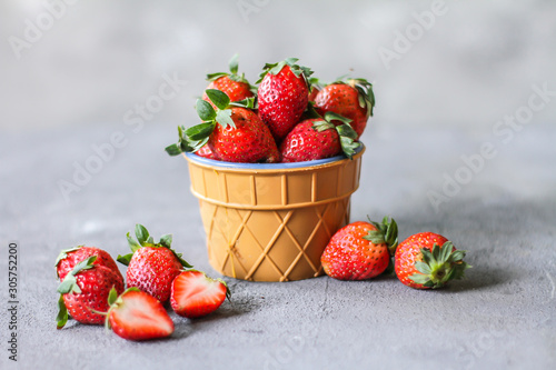 Photo of heap of fresh strawberries in the bowl on rustic grey background..A bunch of ripe strawberries in a bowl on the table. Copy space. Healthy fresh fruit. Organic food. Clear food