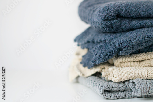 Knitted blankets in a pile on a white background. Copy space.