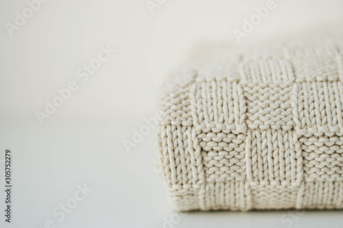 Knitted texture. Beige plaid on a white table on the right. Copy space on the left side.