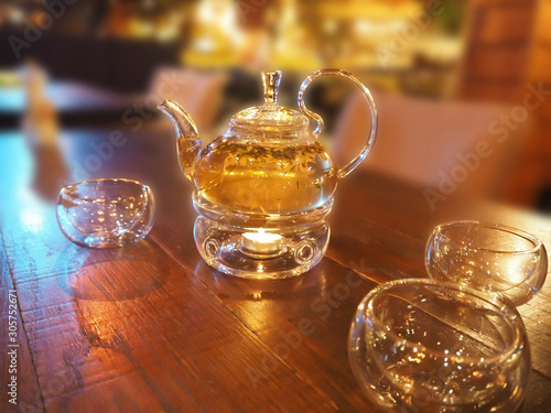 Tea ceremony - glass herbal teapot on wooden table