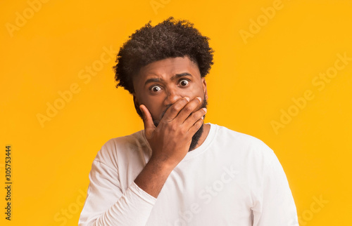 Amazed black man covering his mouth with palm © Prostock-studio