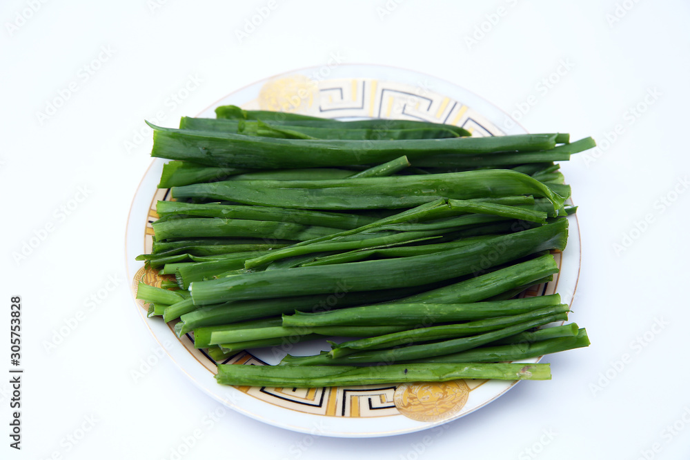 green onion on white background . onions which are green onions white plate with some smaller green onions sliced next to it on a kitchen table. green onion on white background . onions which are green onions white plate with some smaller green onions sliced next to it on a kitchen table.
