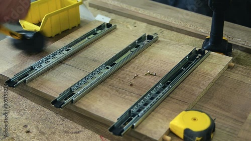 Assembling furniture, installing guides for drawers on furniture panels close-up.