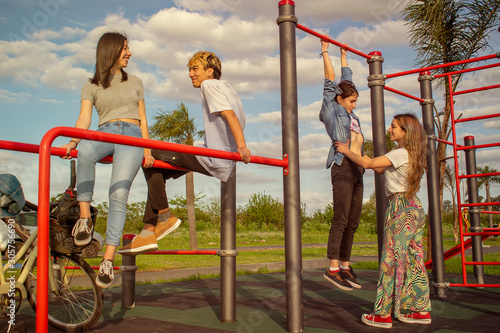 Four teenagers having fun in an outdoor fitness center