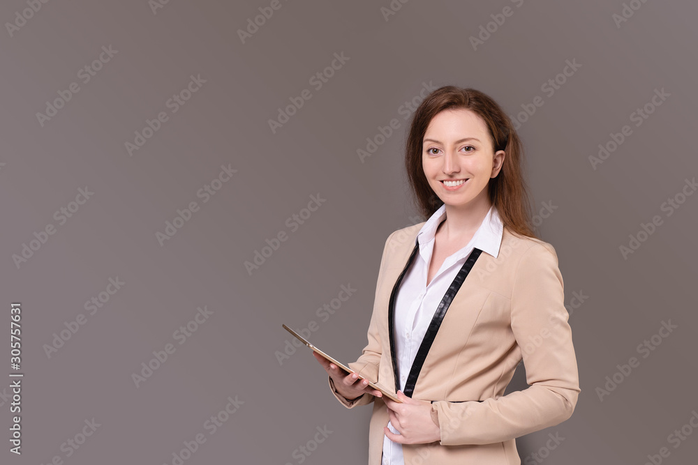 Successful ?aucasian positive elegant businesswoman in a beige jacket and holding a tablet in her hands posing on a purple background. Happy young woman advertises wholesales stores. Advertising space Successful ?aucasian positive elegant businesswoman in a beige jacket and holding a tablet in her hands posing on a purple background. Happy young woman advertises wholesales stores. Advertising space