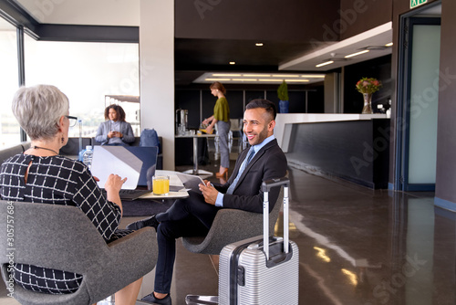 Photos Diverse business partners sitting in modern airport lounge with