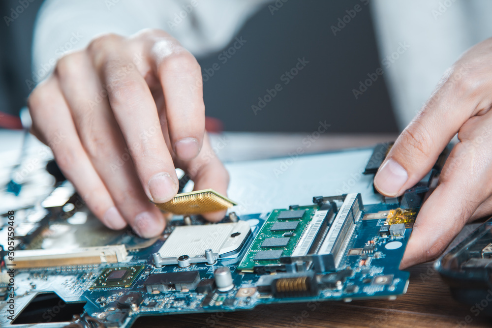 The technician is putting the CPU on the socket of the computer motherboard The technician is putting the CPU on the socket of the computer motherboard