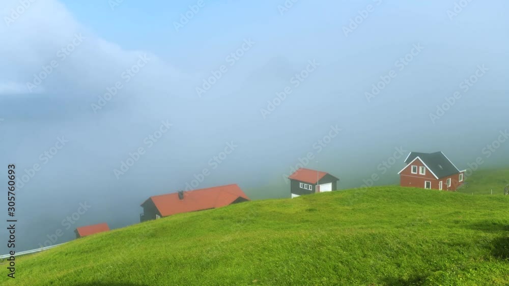 Foggy morning view of a houses with red roofs and foggy sky in the Velbastadur village on Streymoy island, Faroe islands, Denmark. UHD 4k video Foggy morning view of a houses with red roofs and foggy sky in the Velbastadur village on Streymoy island, Faroe islands, Denmark. UHD 4k video