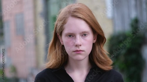 Child loneliness. Sad ginger girl orphan thought. Homeless redhead child is depressed outside the abandoned building.